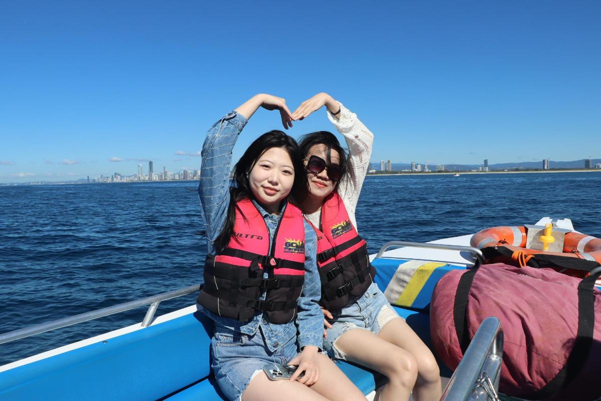 two girls sitting on a boat in the water