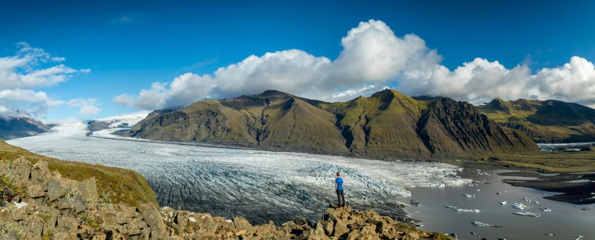 uma pessoa em pé no topo de uma montanha com vista para um rio