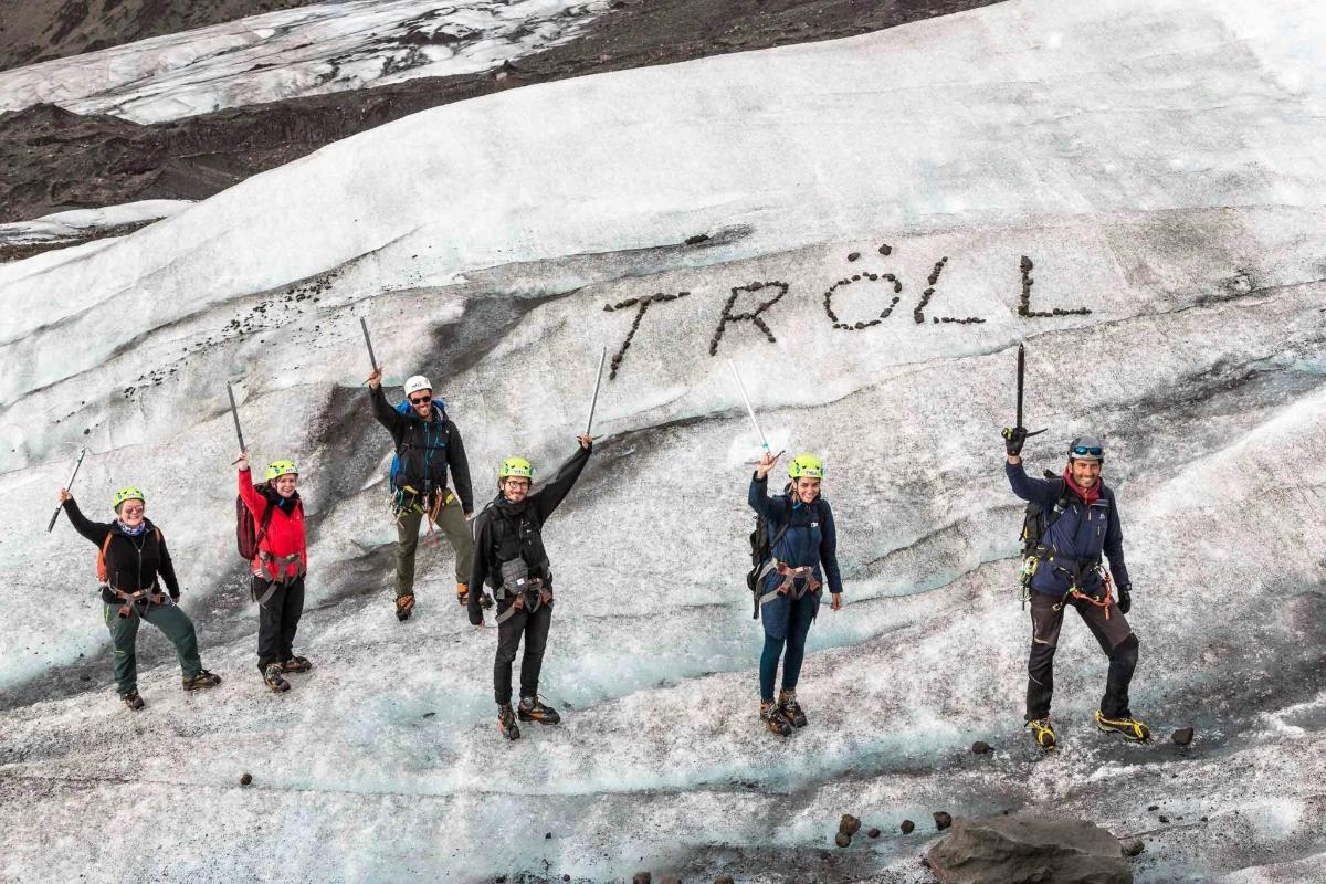 Skupina lidí stojící na ledovci s nápisem troll