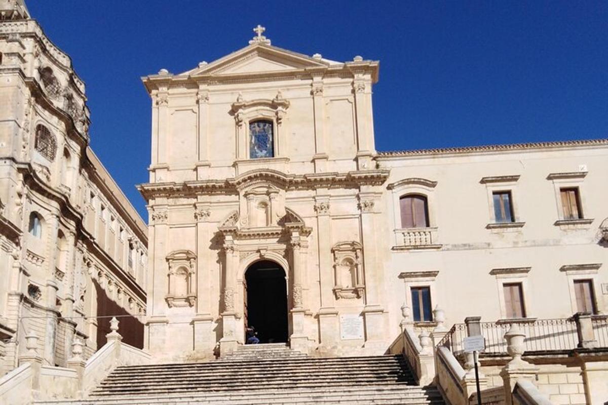 un grande edificio bianco con delle scale di fronte