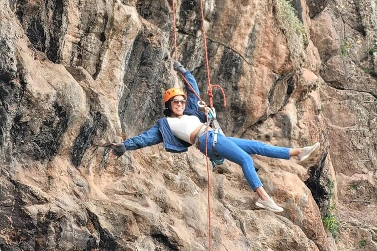 Una mujer está colgada de una cuerda en un acantilado.