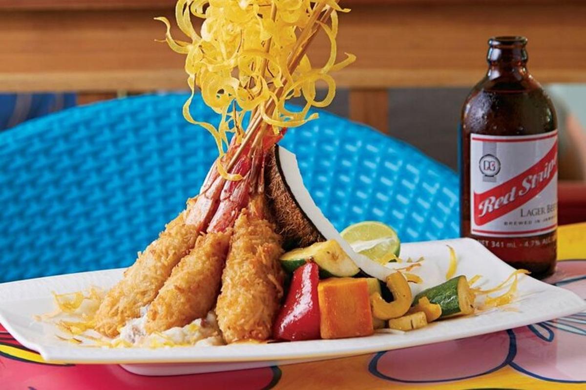 ein Teller mit Essen mit Fischernetzen und Obst und eine Flasche Bier