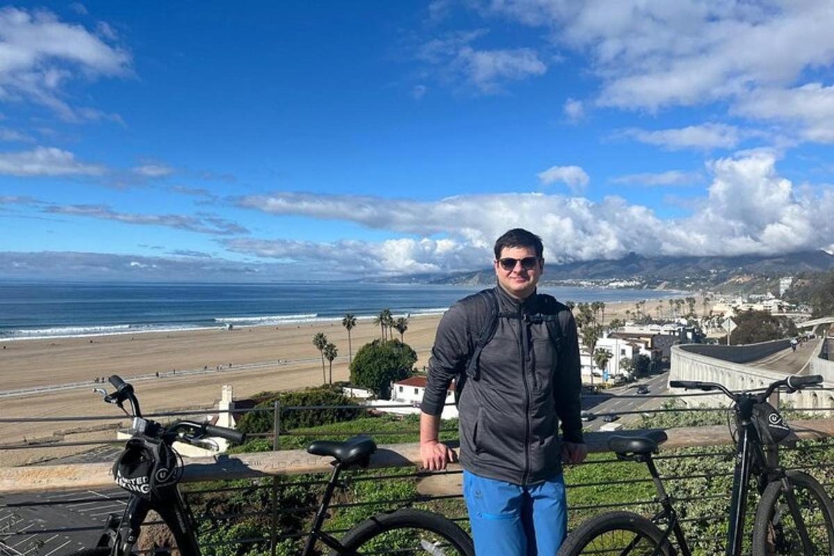 a man standing next to two bikes in front of the beach