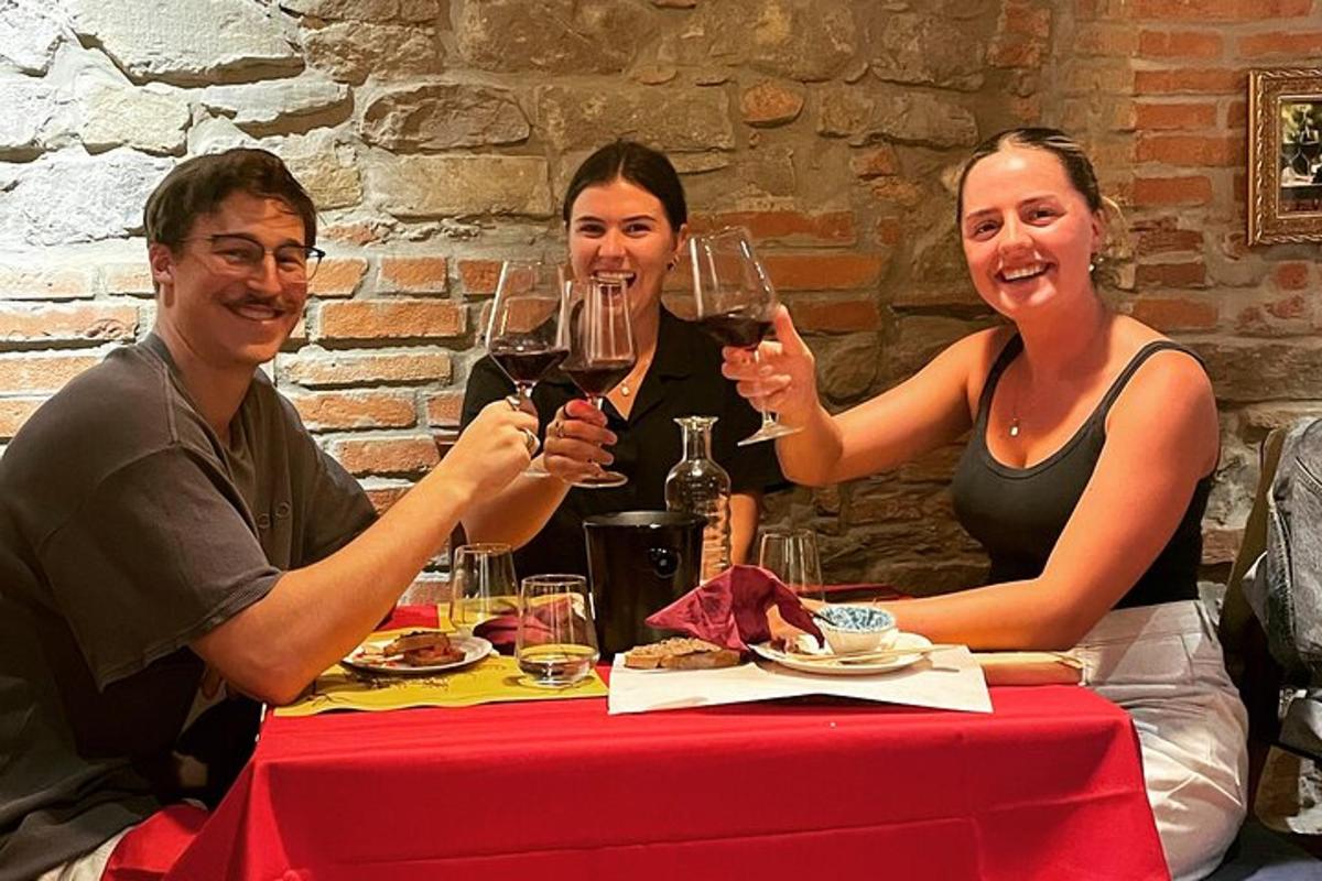 three people sitting at a table with glasses of wine