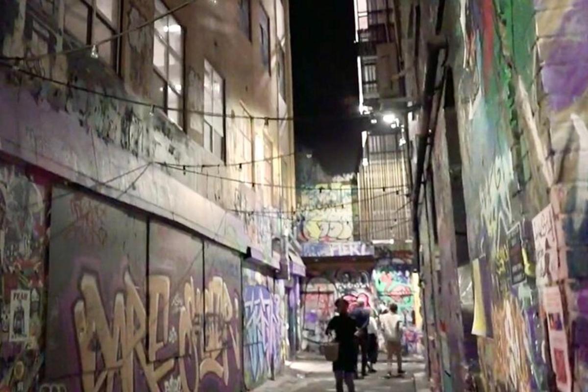 sekumpulan orang berjalan di lorong dengan grafiti