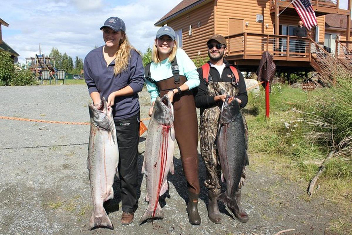 a group of people holding fish in front of a house