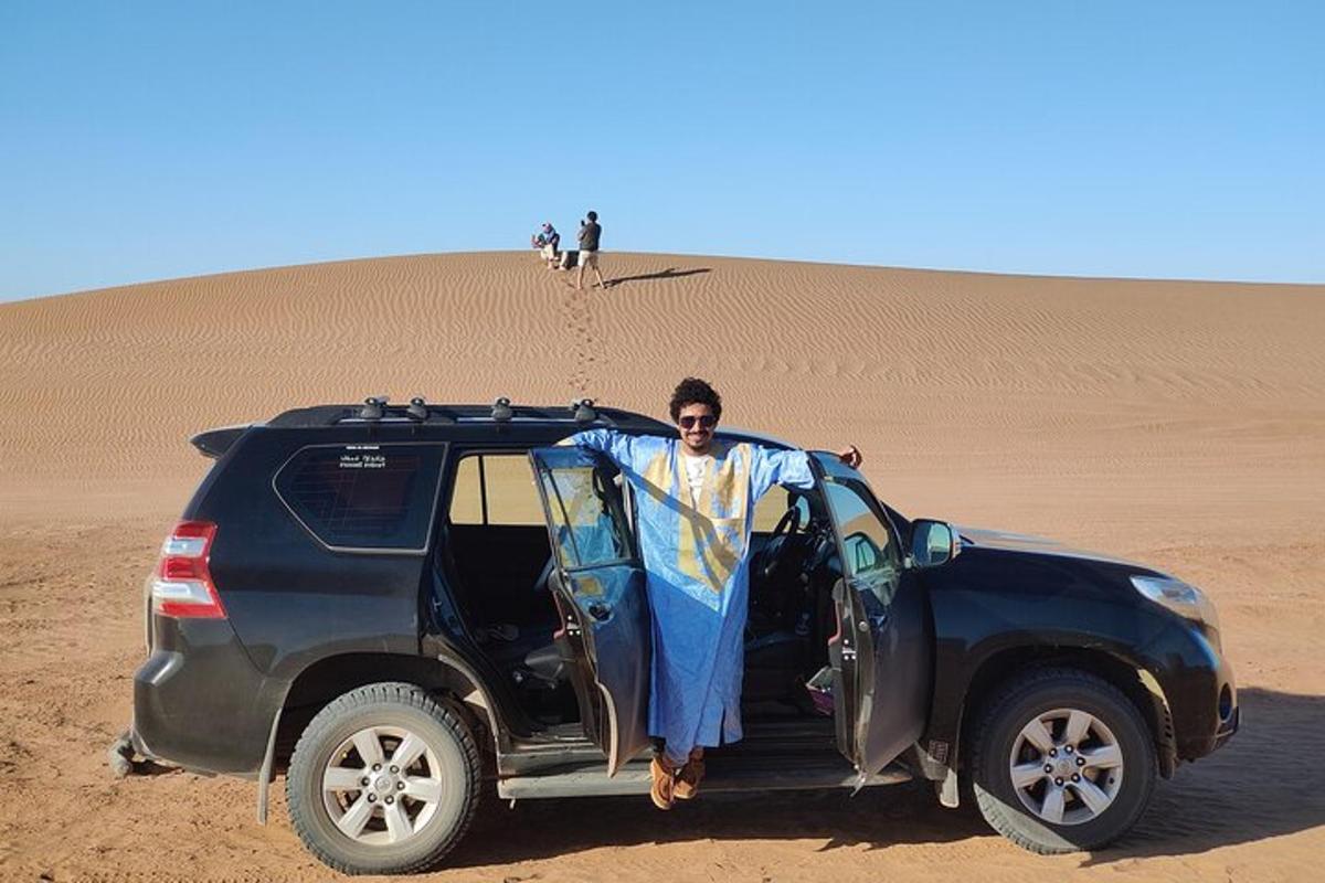 a man standing in the door of a jeep in the desert