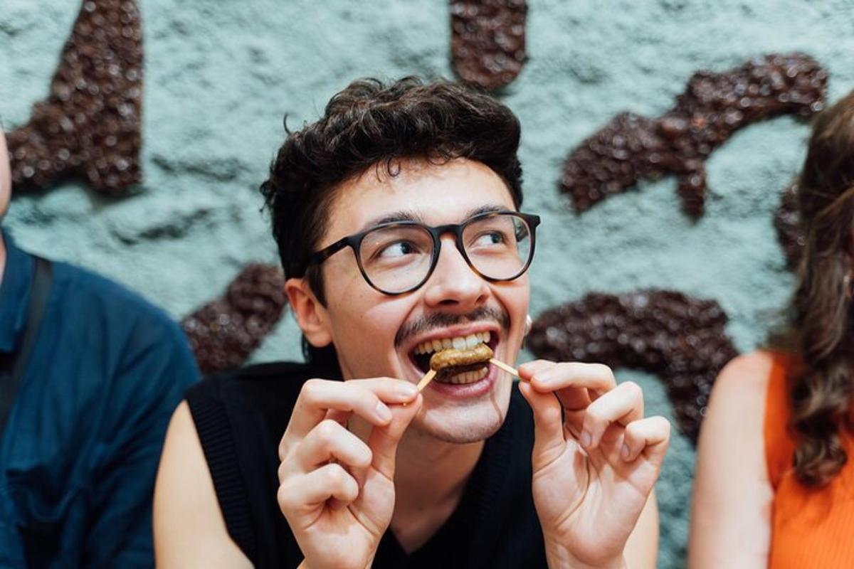 um homem de óculos comendo um pedaço de comida na boca