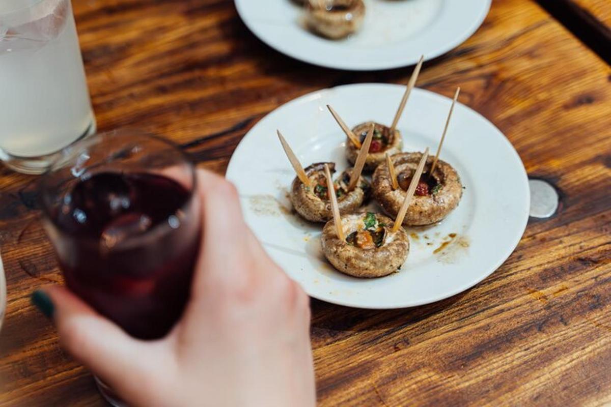 oseba, ki drži kozarec vina in krožnik hrane