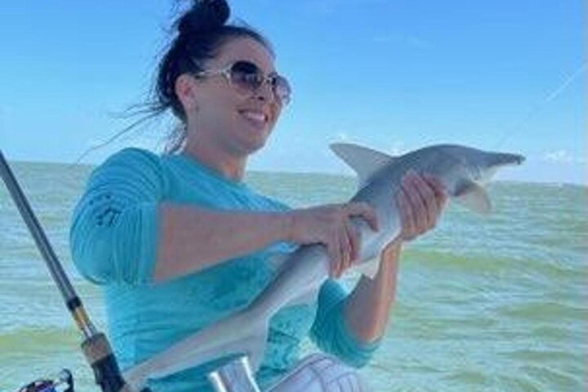 seorang wanita memegang ikan di dalam bot