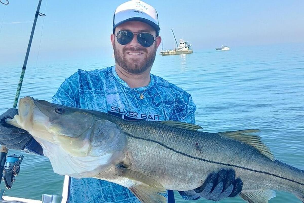 seorang lelaki memegang ikan besar di dalam air
