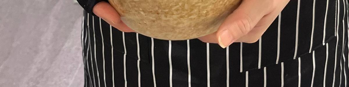 một người mặc áo sơ mi đen đang cầm một chiếc bánh hamburger