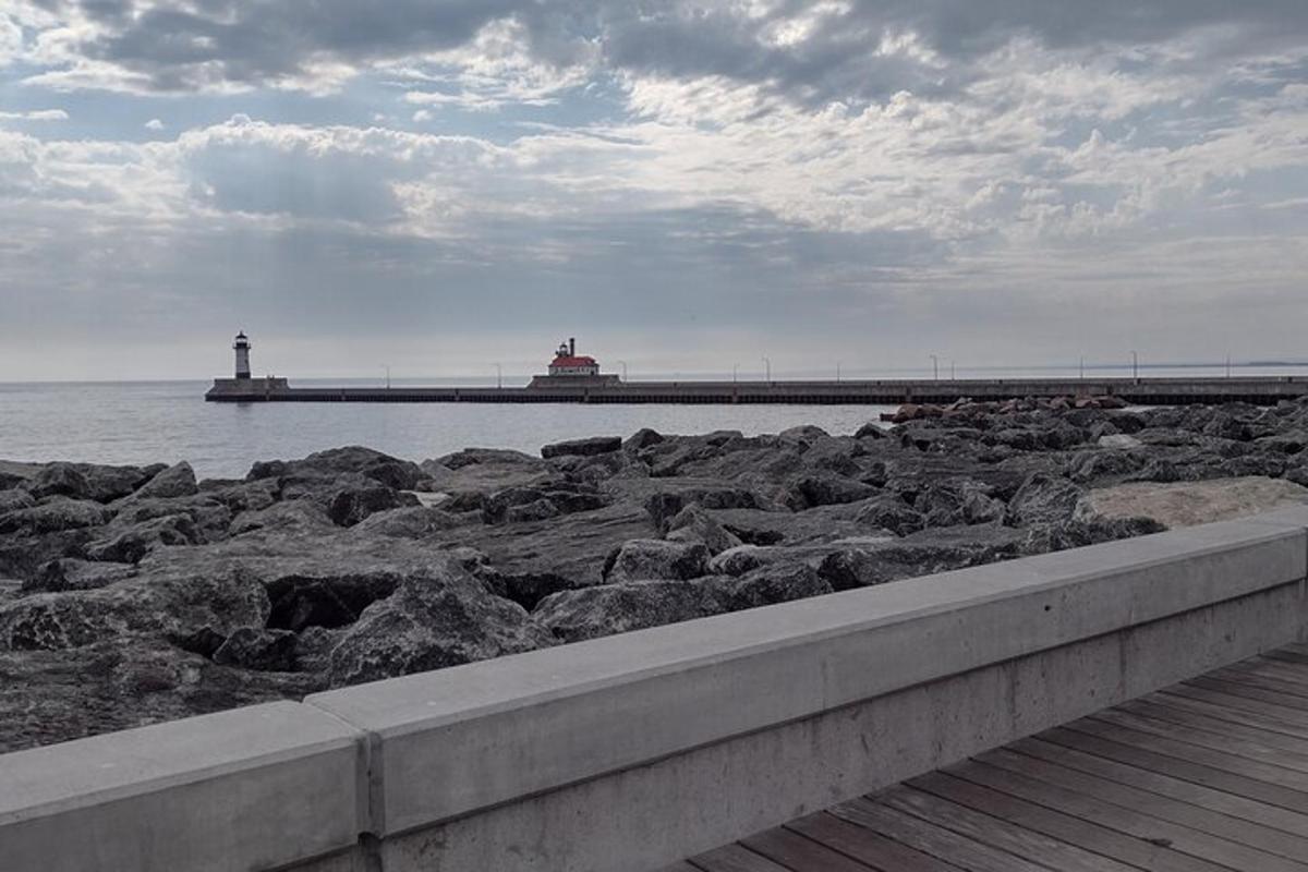 a pier with a lighthouse in the water with rocks