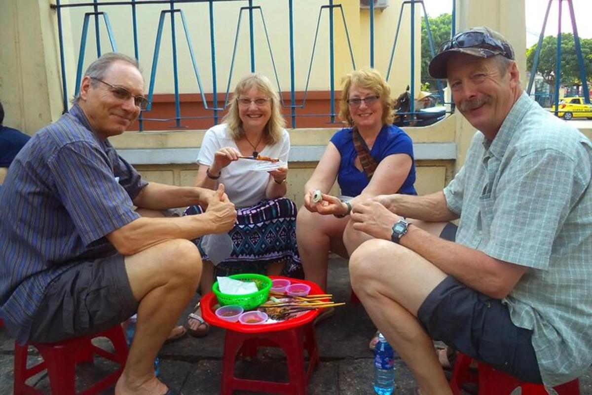 un gruppo di persone sedute su una panchina che mangiano cibo