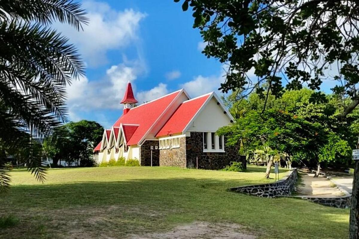 a church with a red roof on a grass field