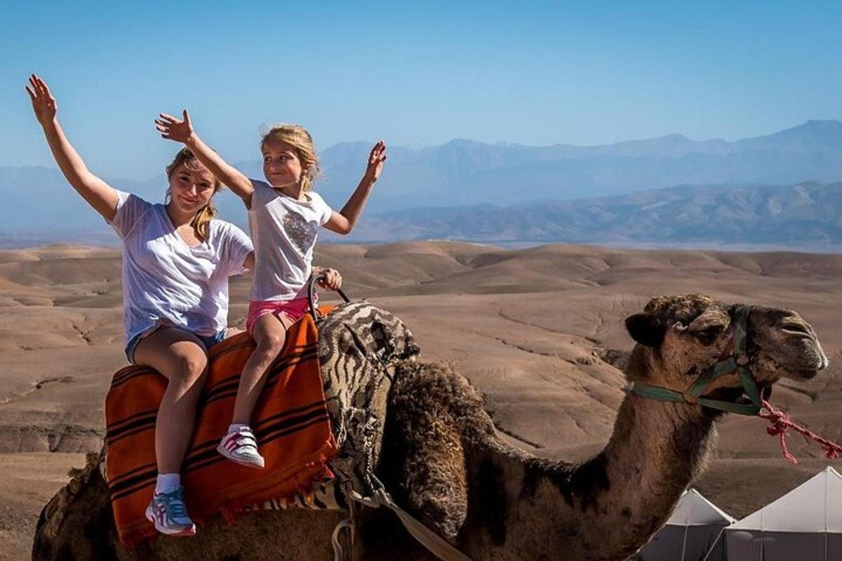 Dos niños viajan en camello por el desierto.