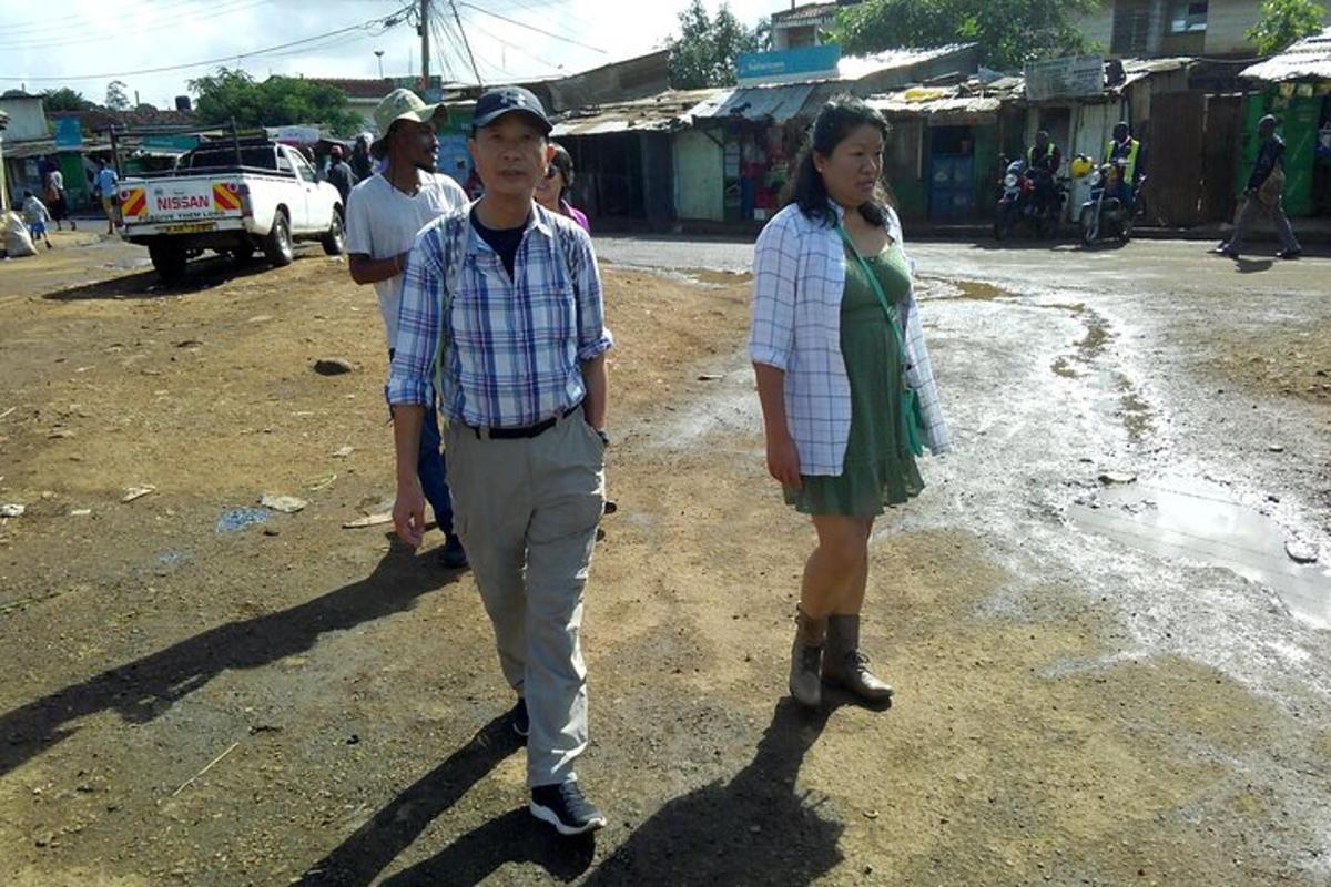 um homem e uma mulher parados em uma estrada de terra