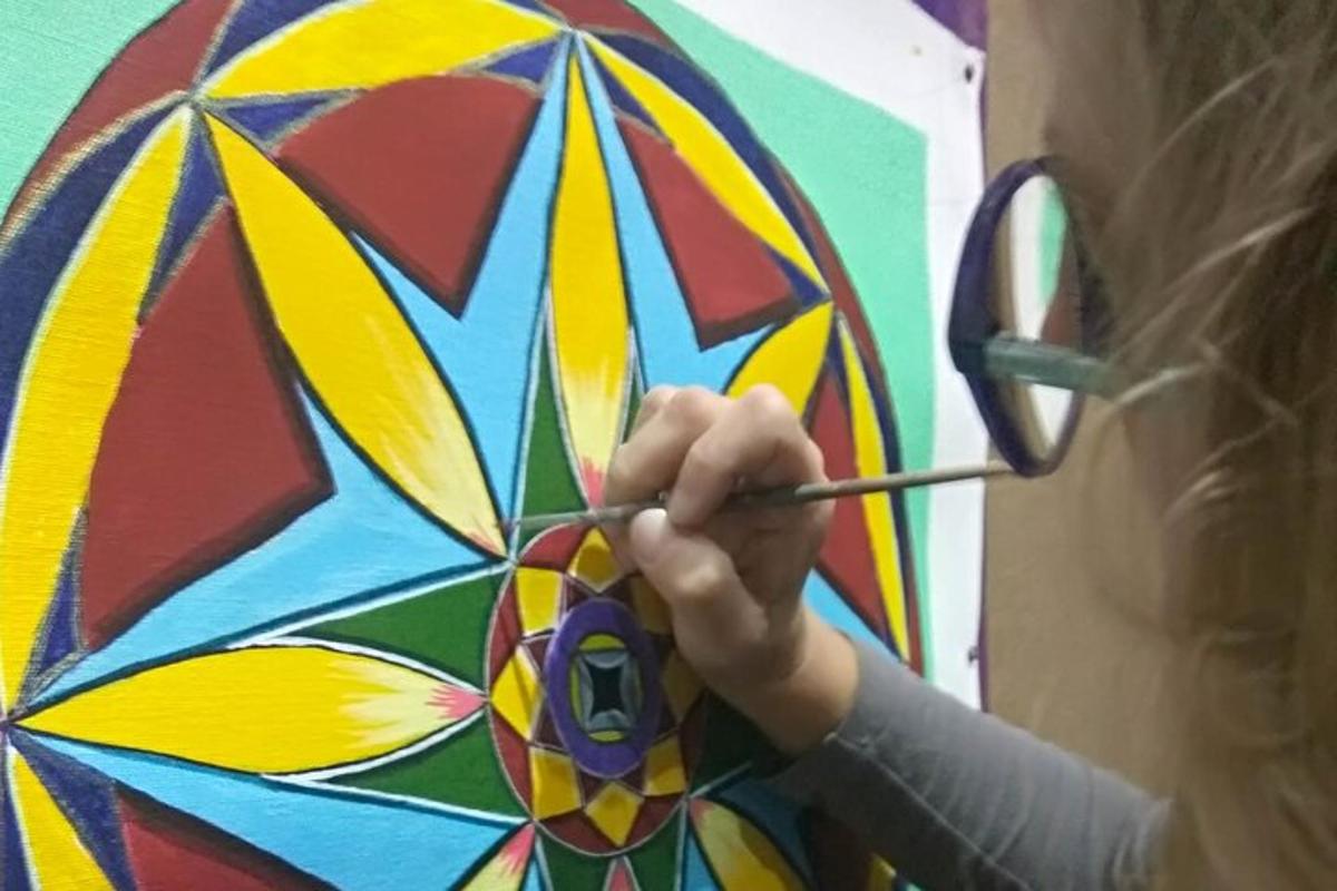 a woman painting a colorful kite with a scissors