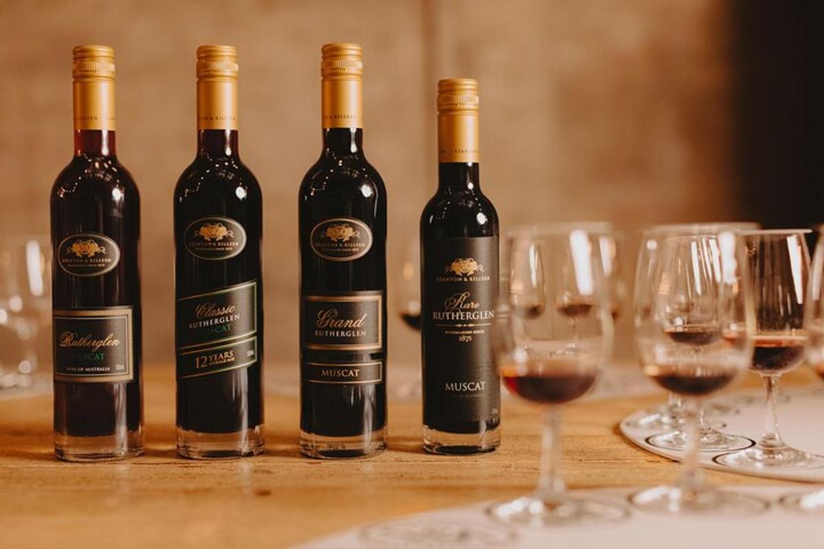 quatro garrafas de vinho sobre uma mesa com taças de vinho