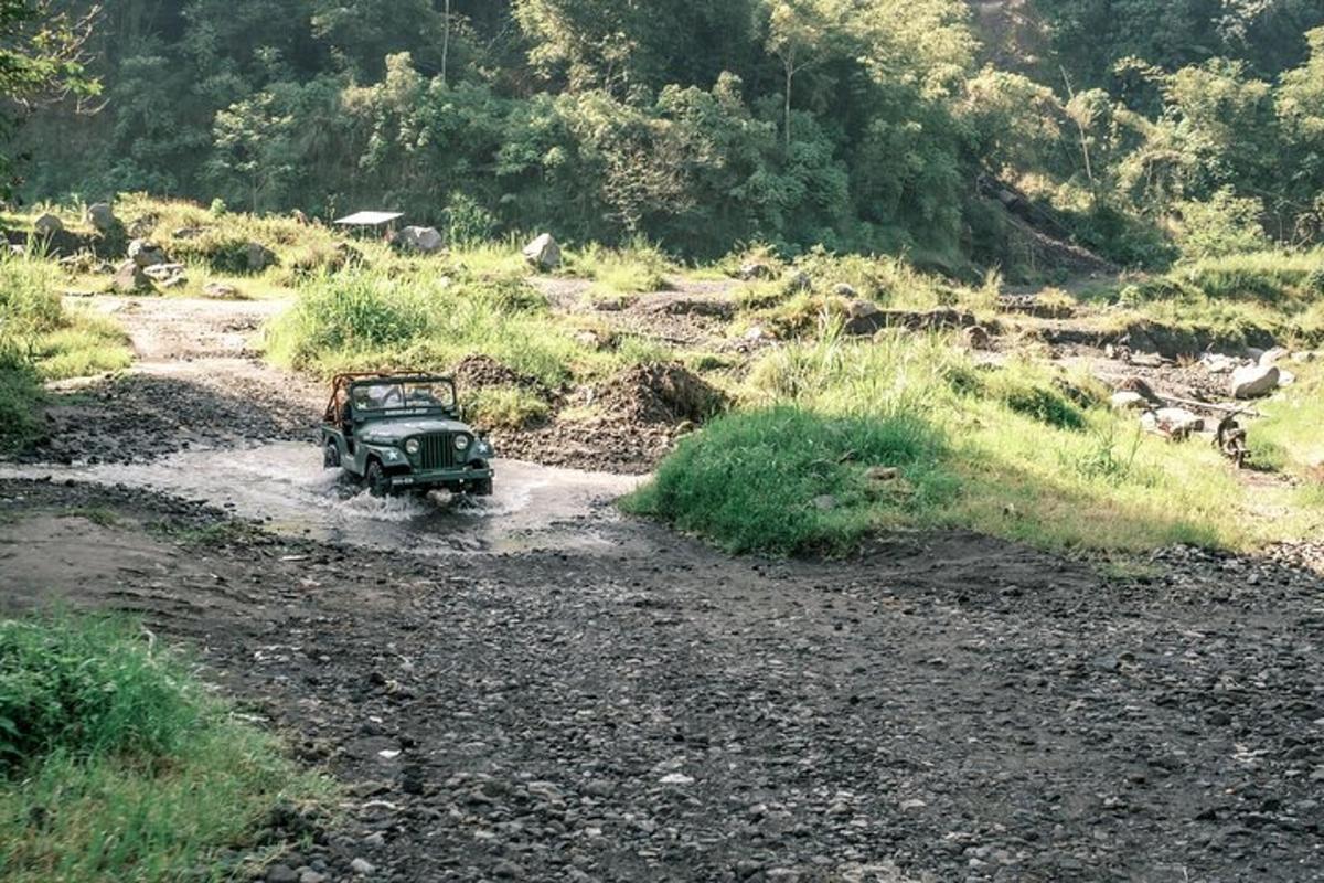 un jeep conduint per un riu en un camp