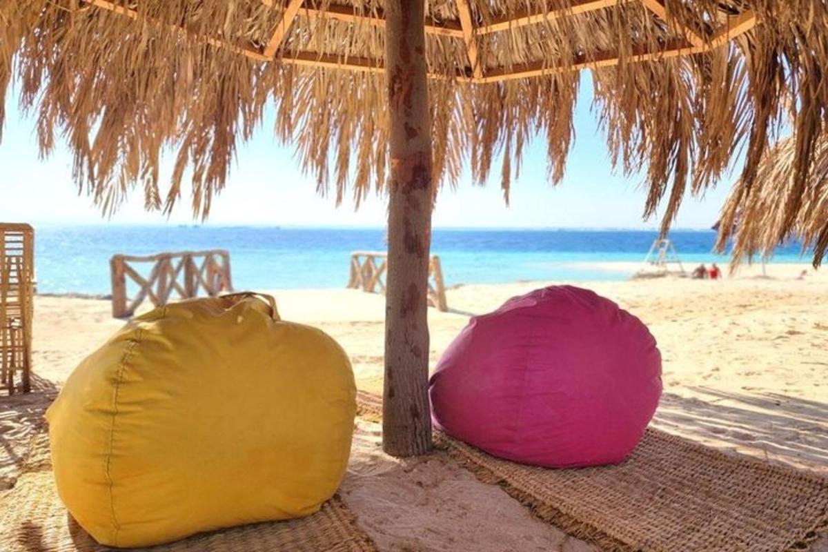 due borse appoggiate su una spiaggia con un ombrellone di paglia