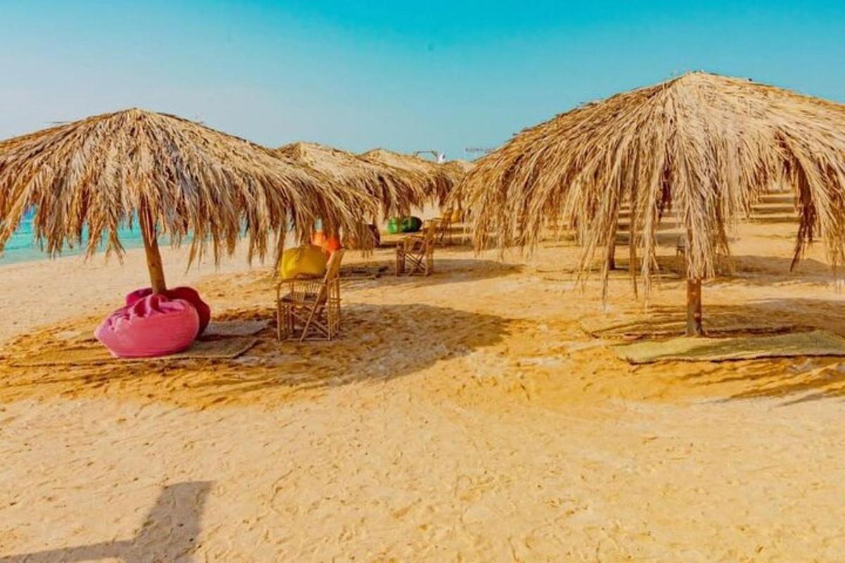 skupina slamnatih senčnikov in stolov na plaži