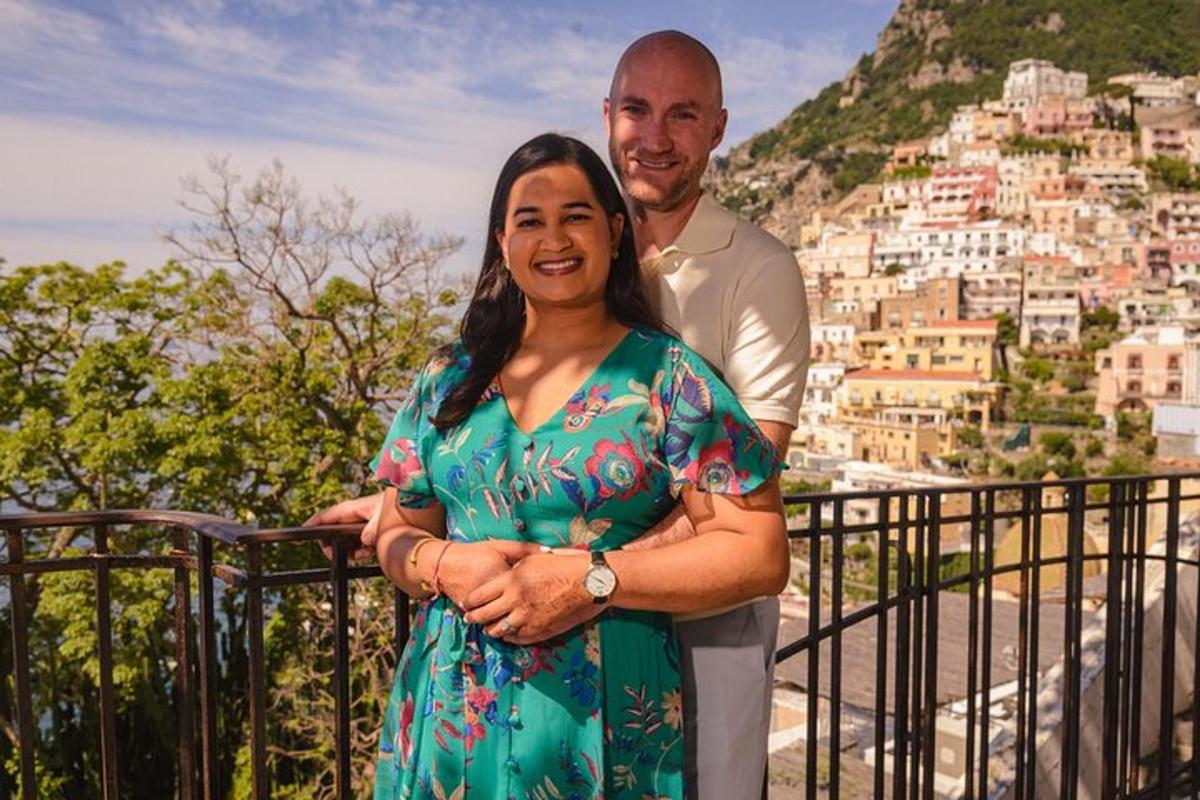 um homem e uma mulher em pé em uma varanda com uma montanha