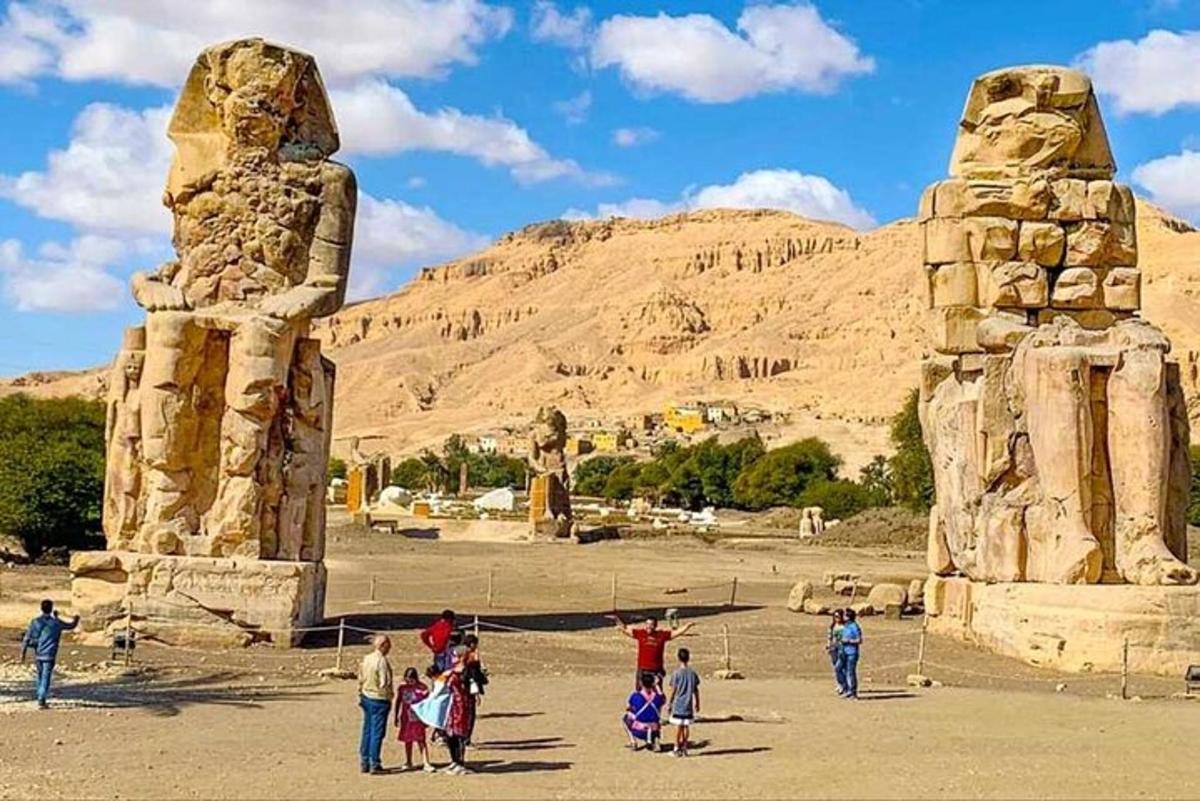 um grupo de pessoas em pé em frente a duas estátuas de pedra