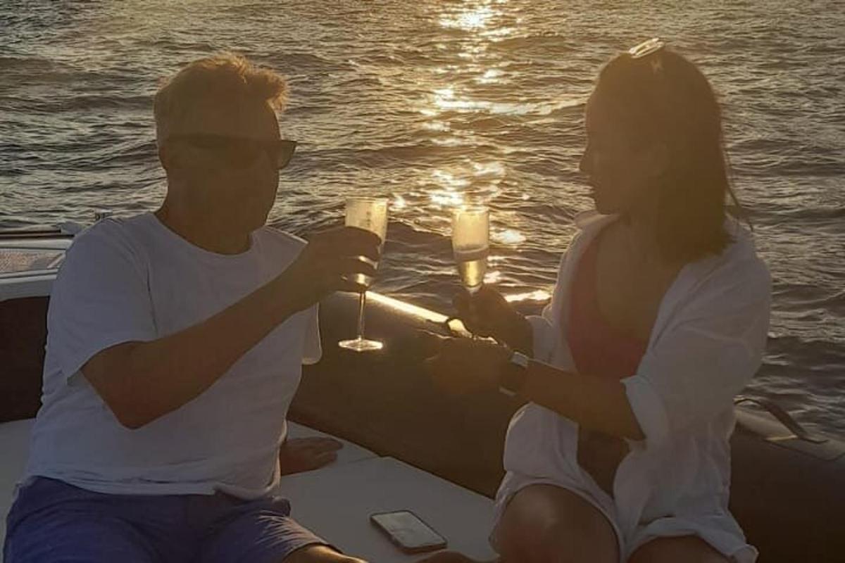 um homem e uma mulher sentados em um barco segurando taças de champanhe