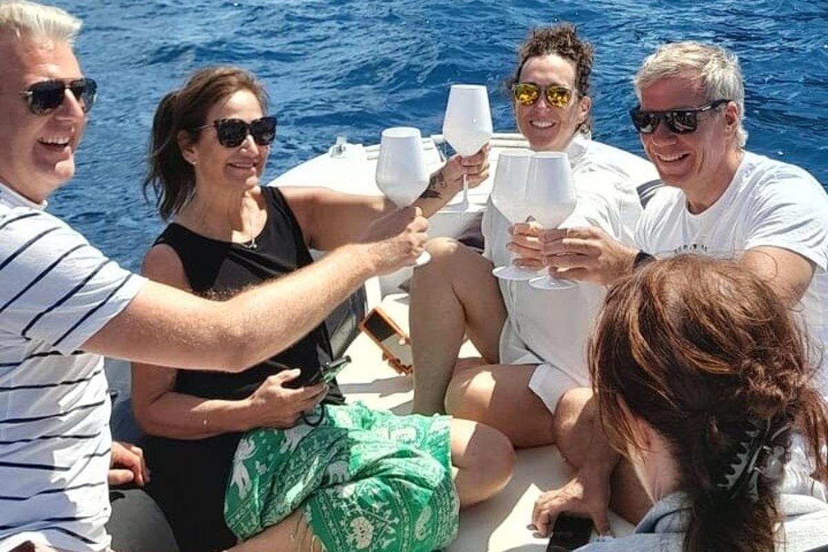 um grupo de pessoas sentadas em um barco bebendo vinho