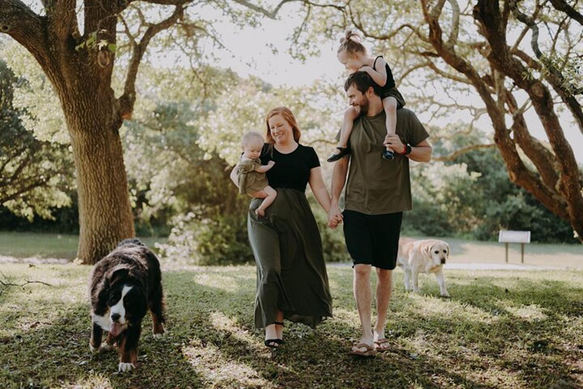 a man and woman walking with a baby and two dogs