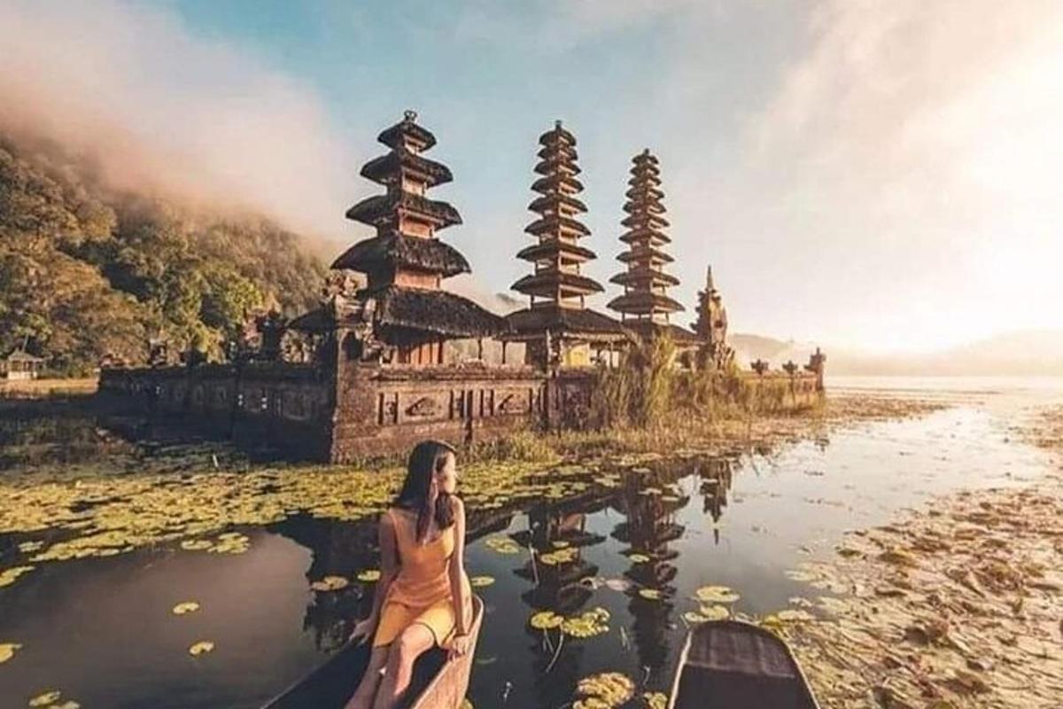 a woman in a boat on the water in front of a temple