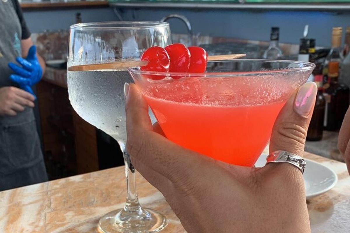 a person holding up a drink with cherries in it