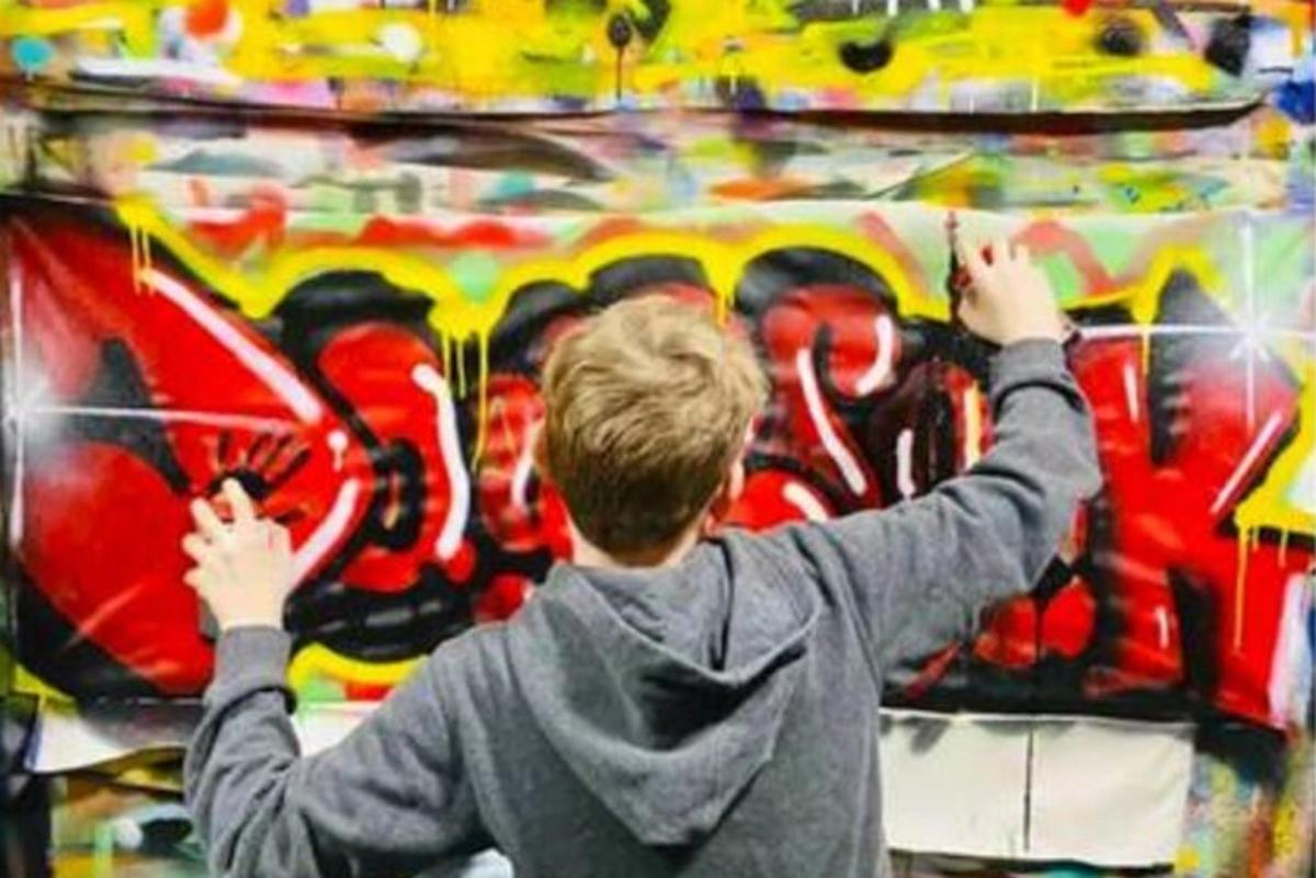 seorang budak lelaki melukis dinding dengan grafiti