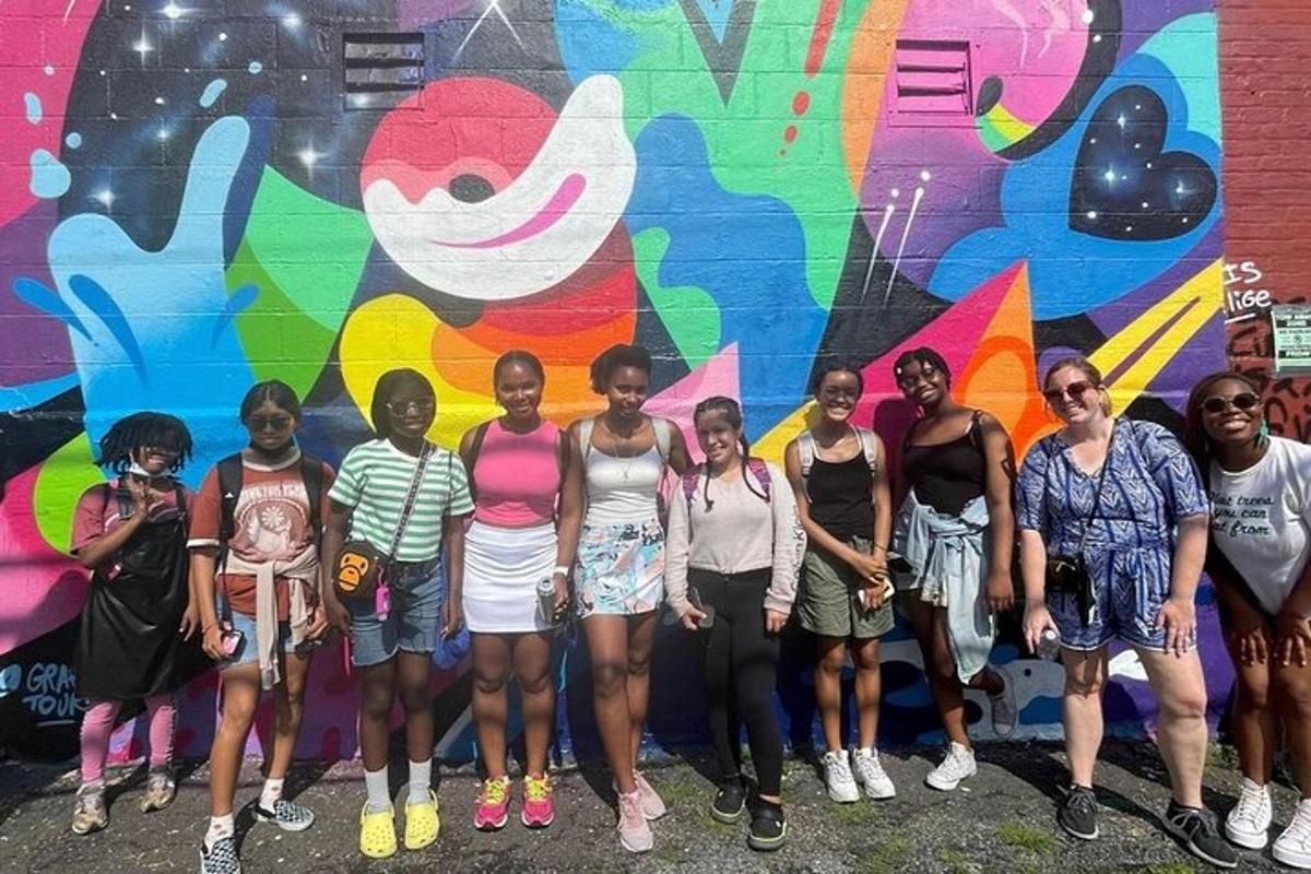 sekumpulan orang berdiri di hadapan mural