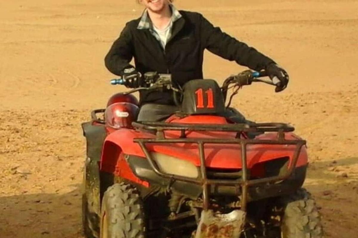 un home que condueix un quad al desert