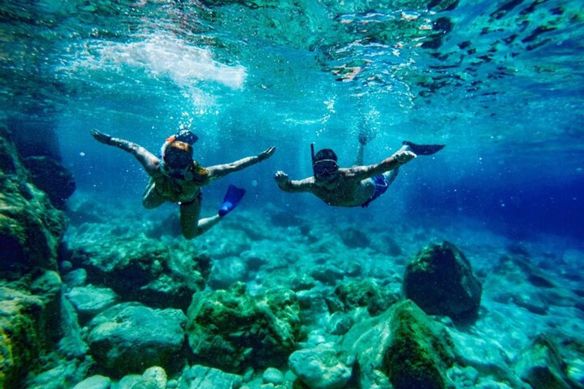 Dos personas nadando en el agua cerca del arrecife.