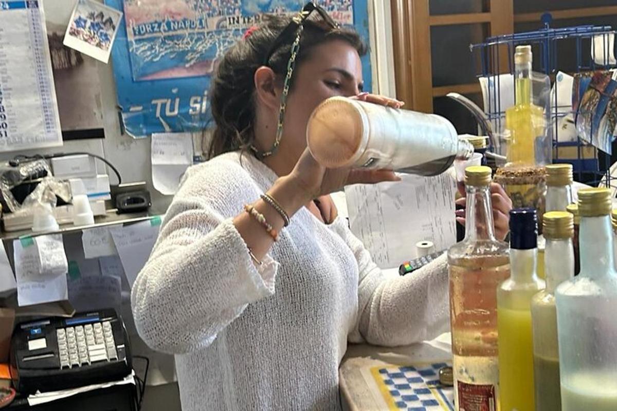 een vrouw die aan een toonbank staat en uit een fles drinkt