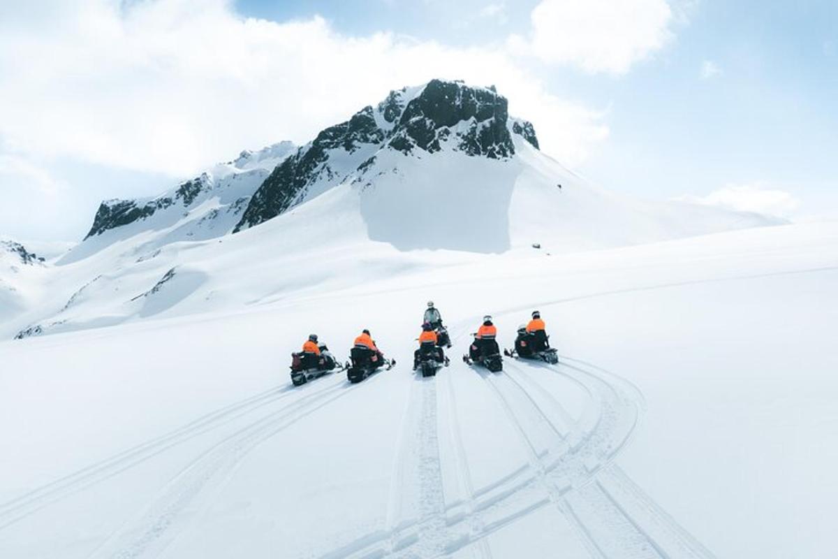 un grup de oameni care merg pe motociclete prin zăpadă