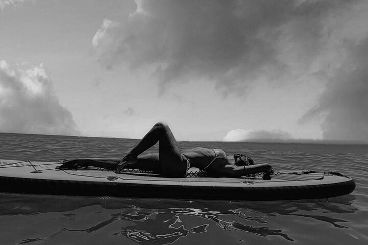 osoba ležící na paddleboardu ve vodě