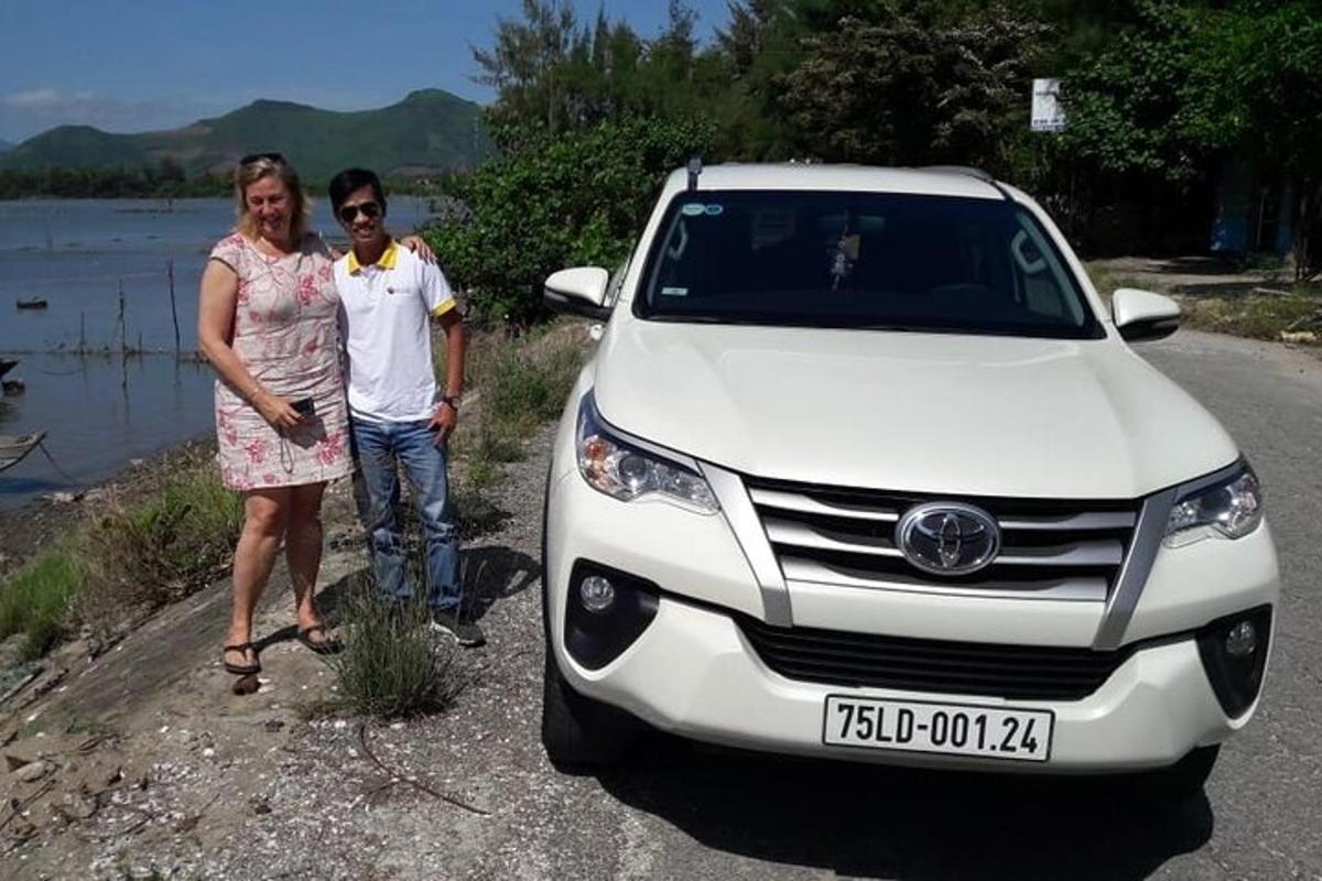Un hombre y una mujer de pie junto a un coche blanco.
