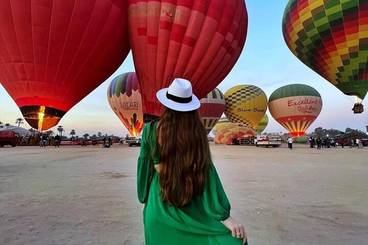 Una mujer con sombrero mirando un montón de globos aerostáticos.