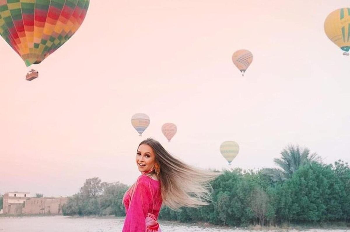 Una mujer con un vestido rosa parada frente a globos.
