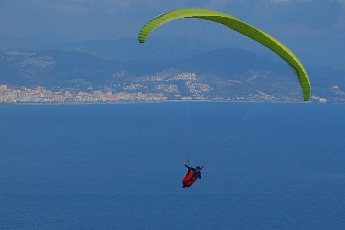 a person riding a parachute in the air over the water