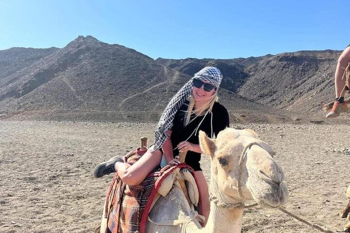 a woman riding on the back of a camel in the desert