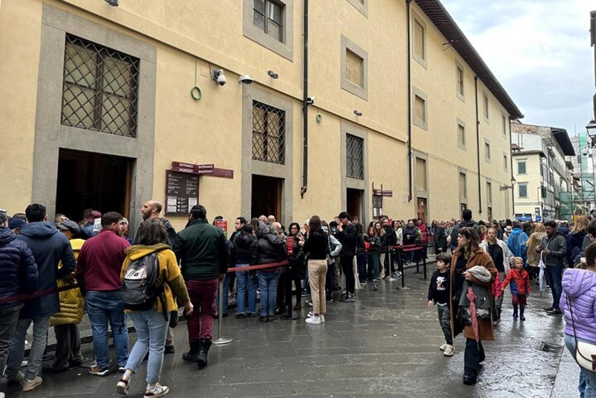 una multitud de persones que estan dretes fora d'un edifici