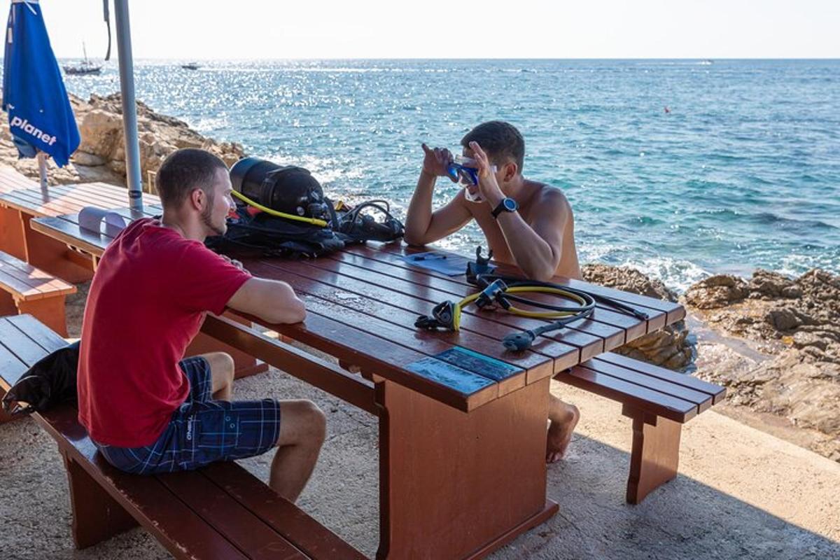 dois homens sentados em uma mesa de piquenique tirando fotos do oceano