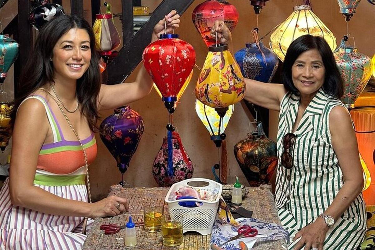 Dos mujeres de pie frente a una mesa con jarrones.