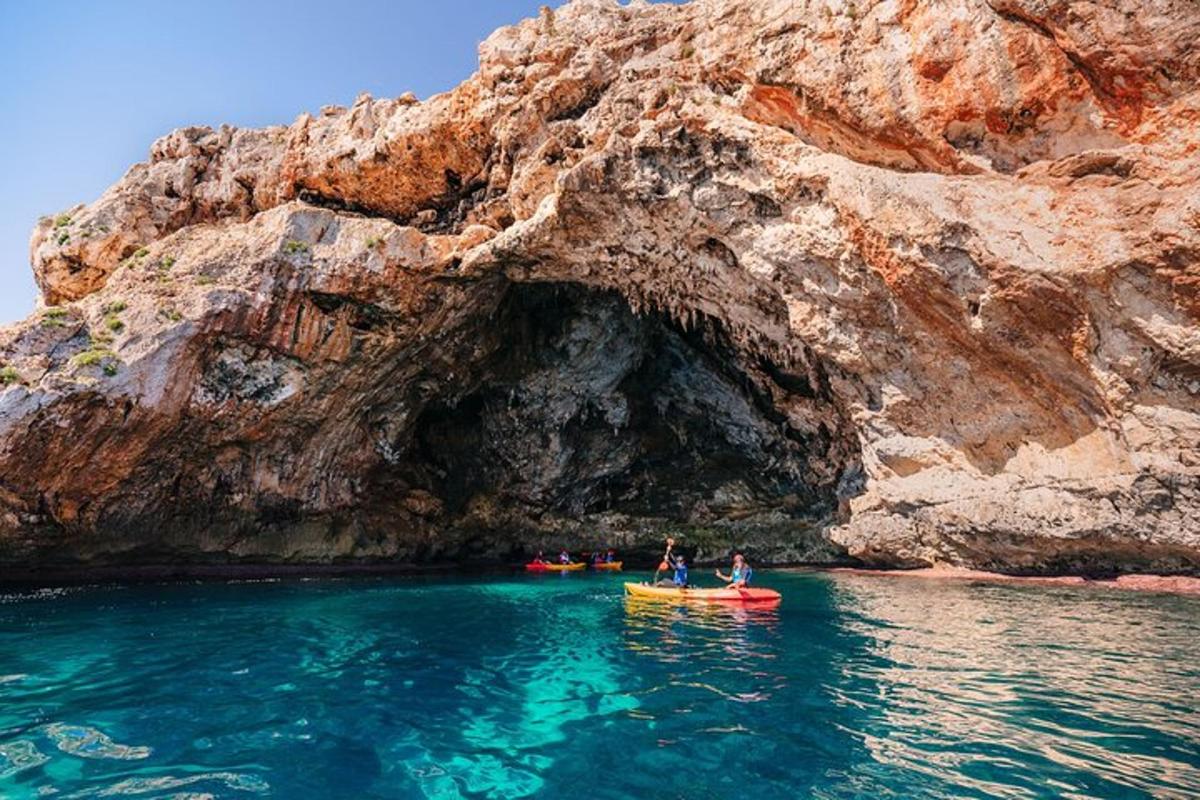 two people in a kayak in front of a cave