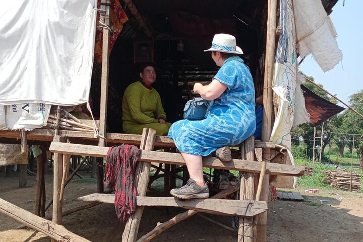 Una mujer sentada en una plataforma de madera en una choza.